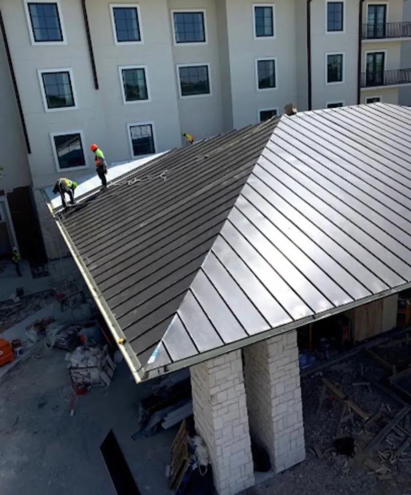 Crew installing standing seam metal roof panels on a commercial project in La Junta
